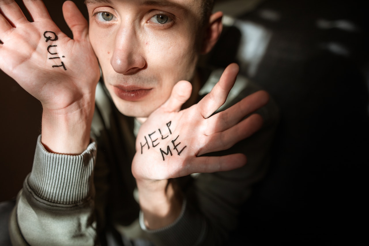 A guy with the help me written on the hand
